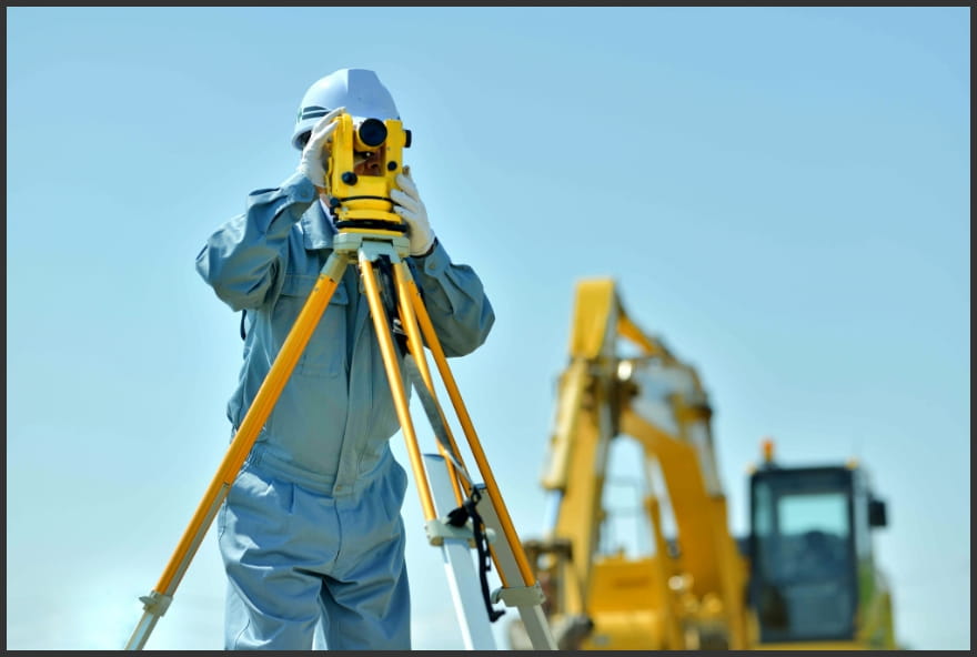 測量機器を使って土地調査を行う作業員